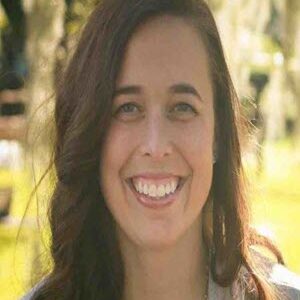 white woman with a smile in front of tree